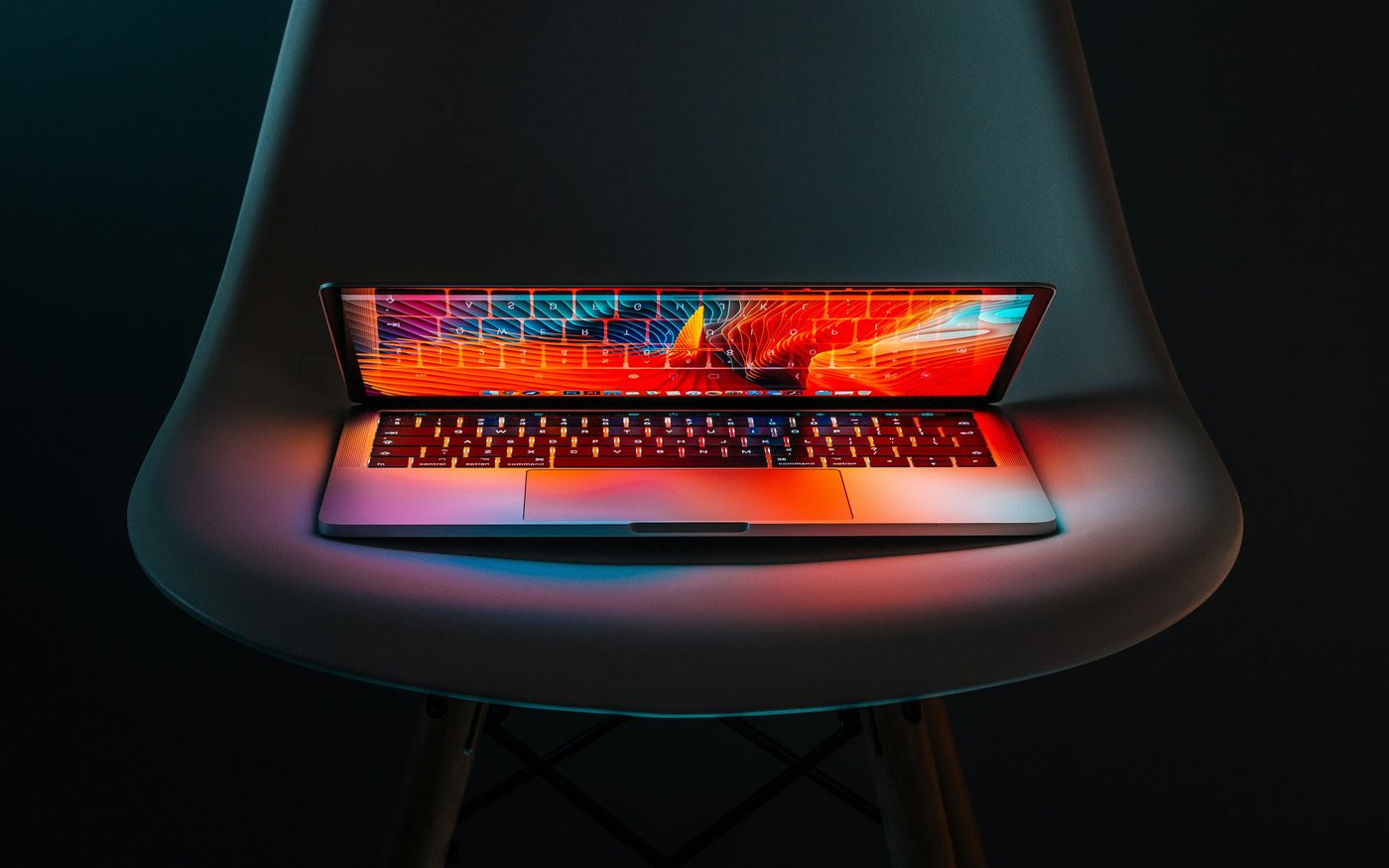 Laptop glowing with code on a dark chair